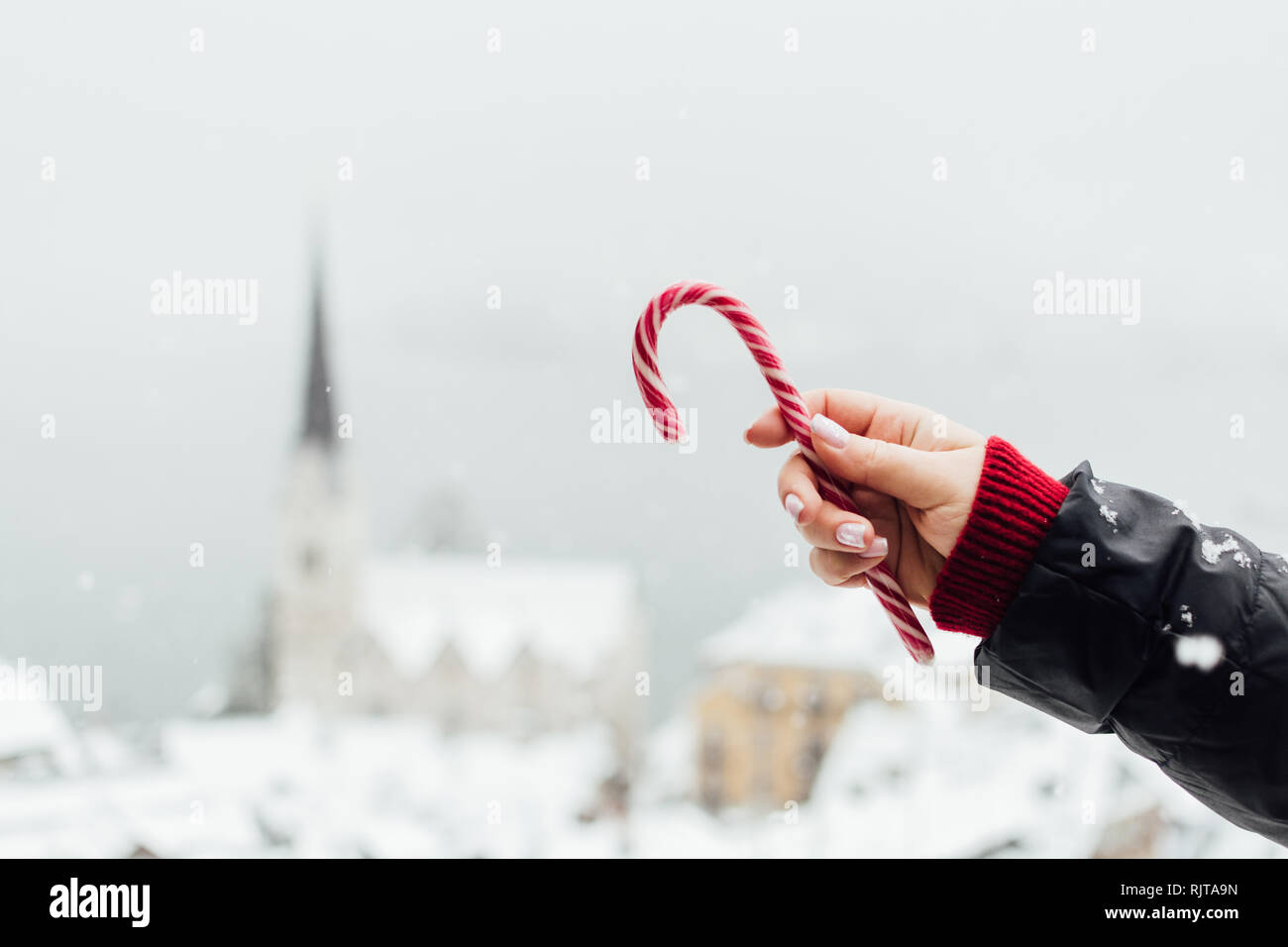 Frau mit roten candycane mit schneebedeckten Hallstatt Altstadt auf Hintergrund, Österreich Stockfoto