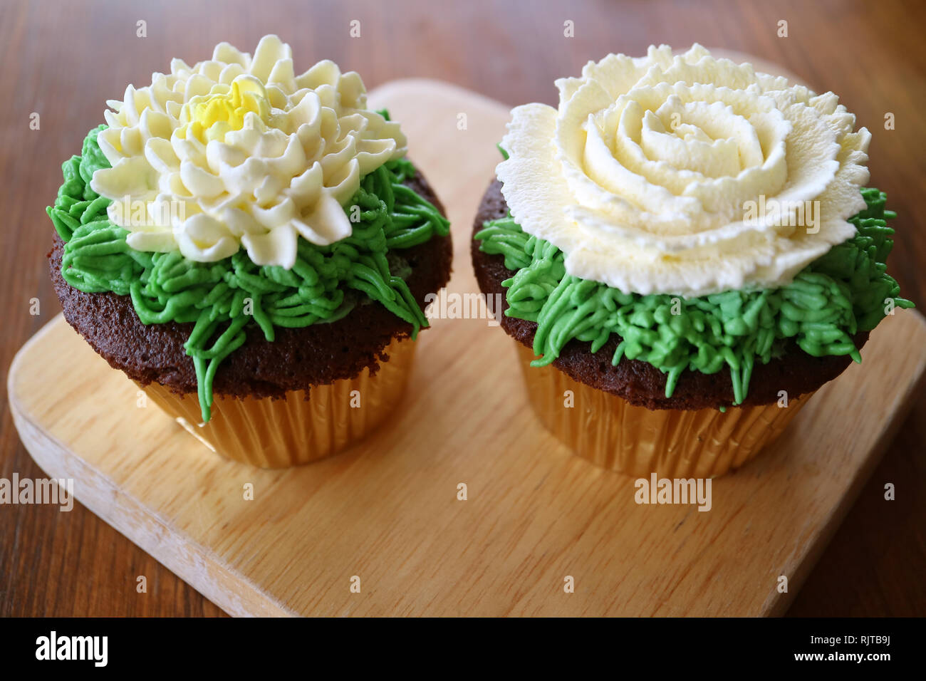 Paar Cupcakes mit Blume geformte Creme auf Holz Tablett serviert Schlagsahne eingerichtet Stockfoto