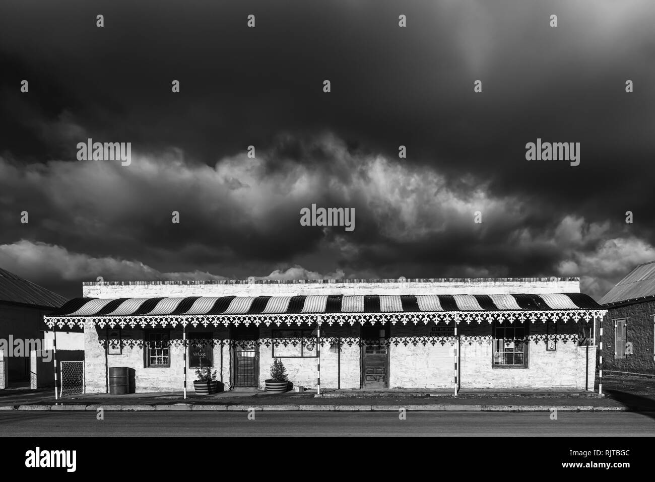 SUTHERLAND, SÜDAFRIKA, August 7, 2018: eine Straße, Szene, mit einem antiken Shop und dunkle Wolken, in Sutherland in der Northern Cape Provinz. Monochrom Stockfoto