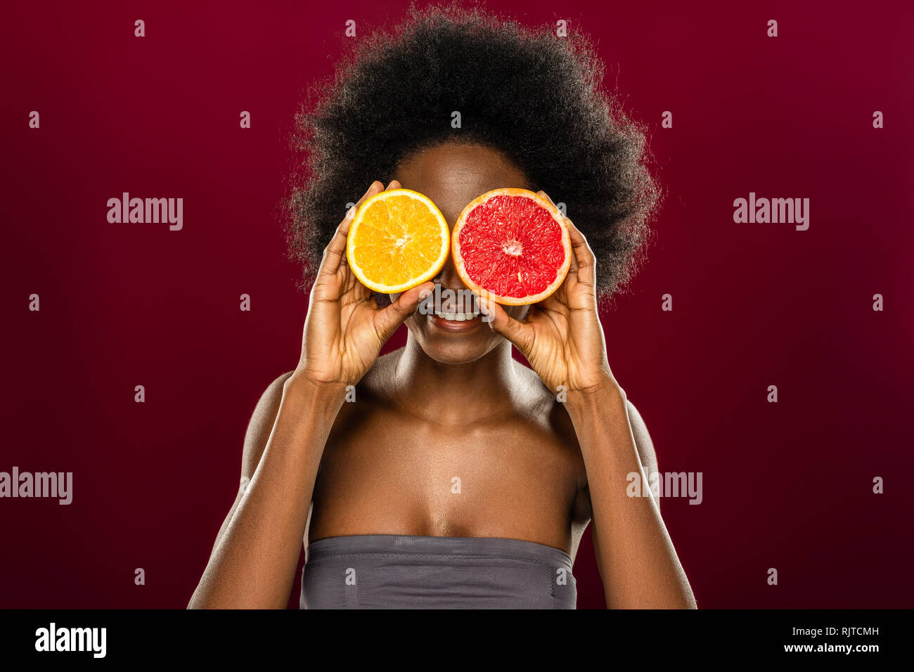 Freudige schöne Frau mit zwei Früchte Hälften Stockfoto