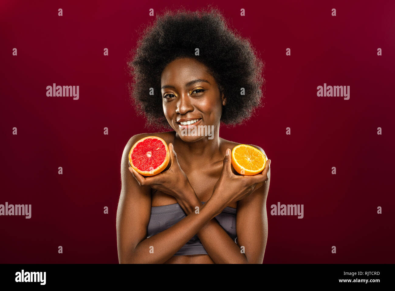 Schöne positive Frau zeigt Ihnen zwei Früchte Hälften Stockfoto