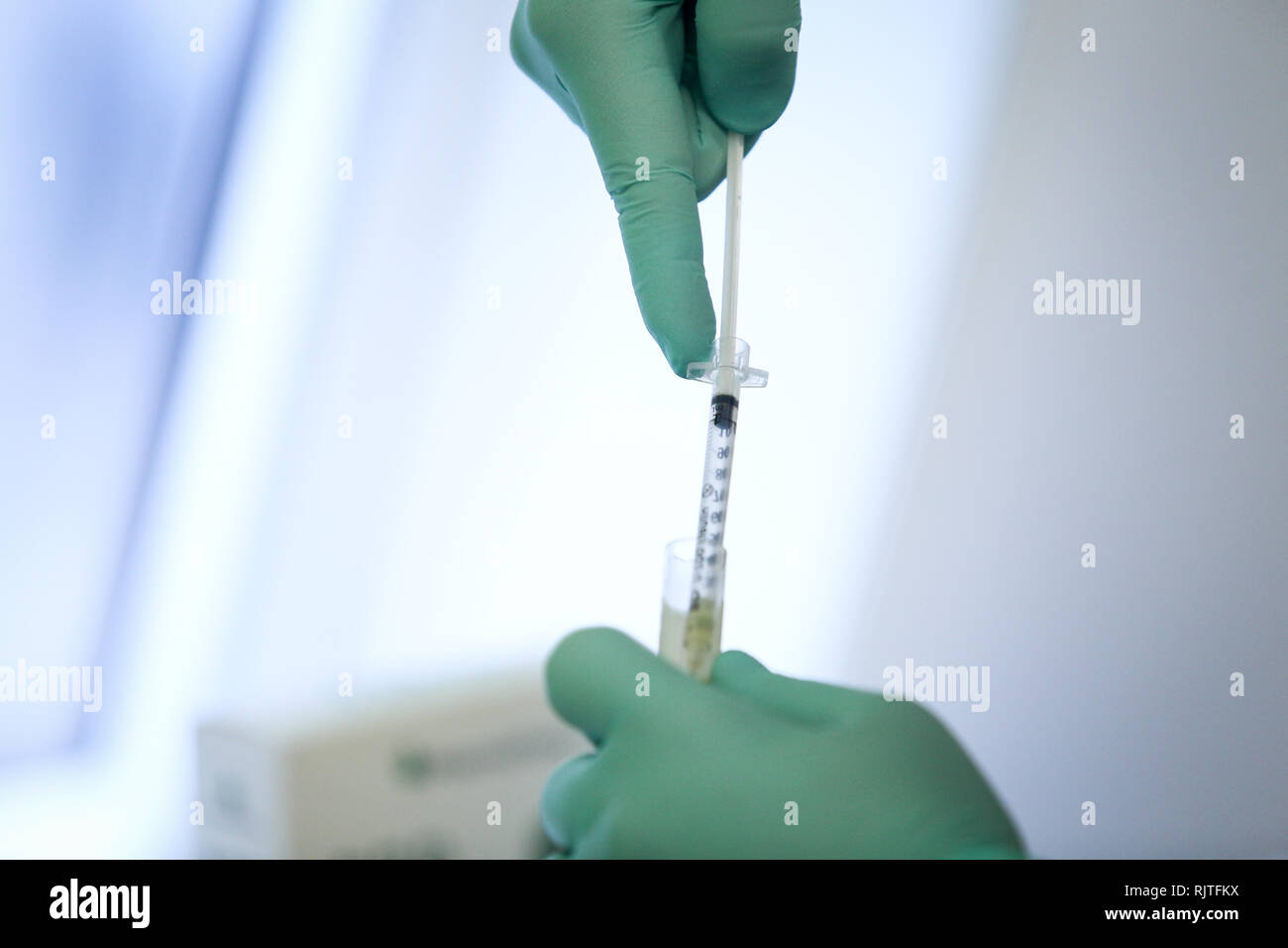 Details mit den Händen eines Arztes, strapazierfähiges Gummi OP-Handschuhe und Extrahieren von Blut und Blutplasma aus der Durchstechflasche mit einer Spritze Stockfoto