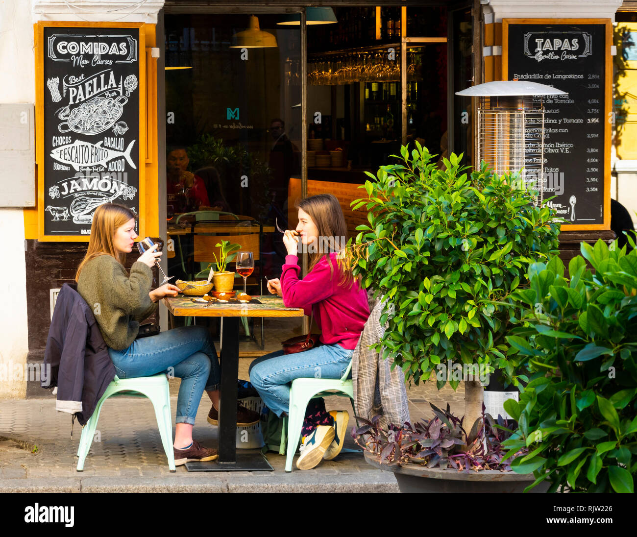 Zwei junge Damen mit einem Drink und einem Snack in einer Tapas Bar in Sevilla, Spanien Stockfoto