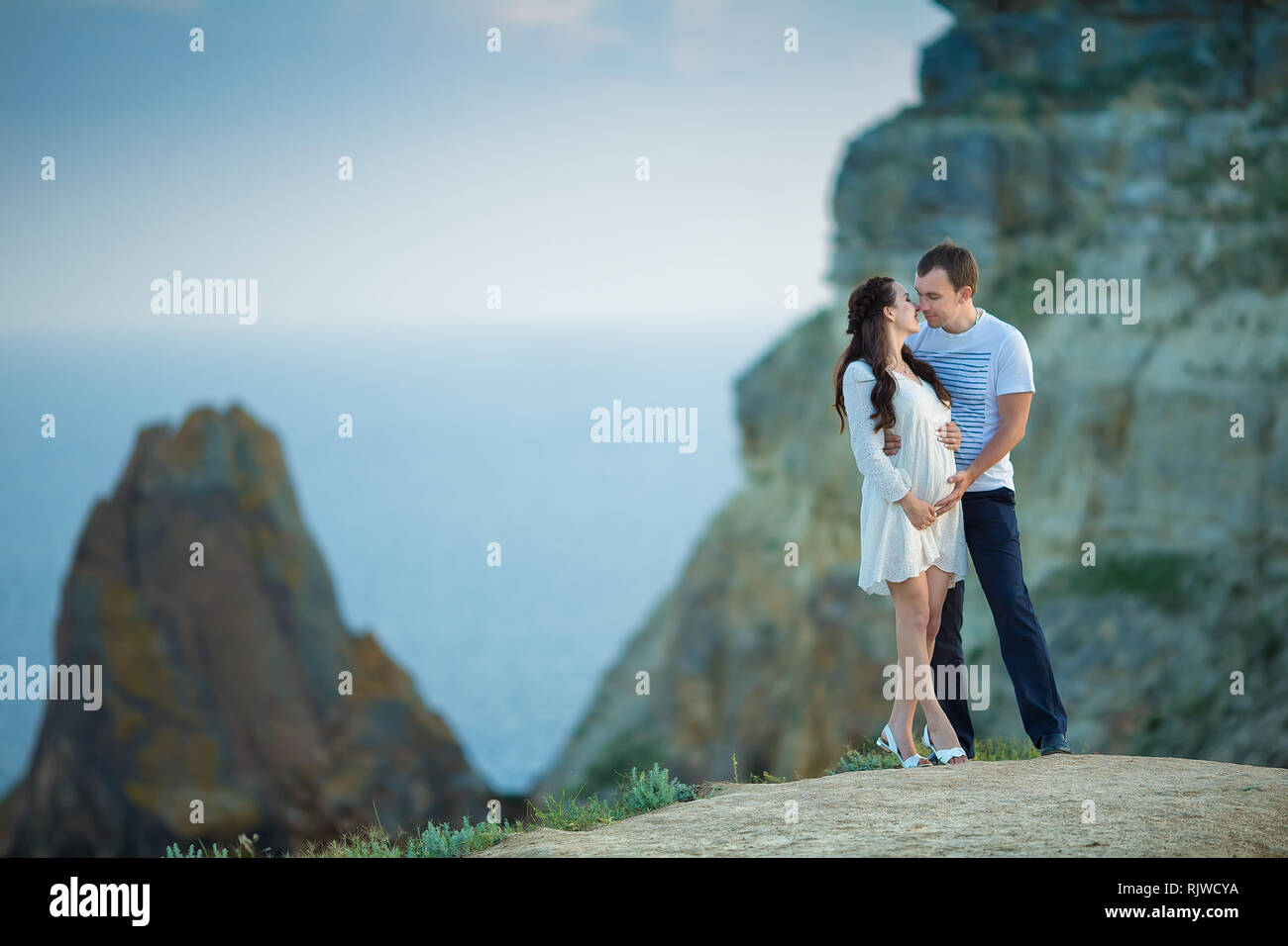 Schöne junge Paar erwarten Baby auf Bergblick mit blauen Meer posiert als Hintergrund. Stockfoto