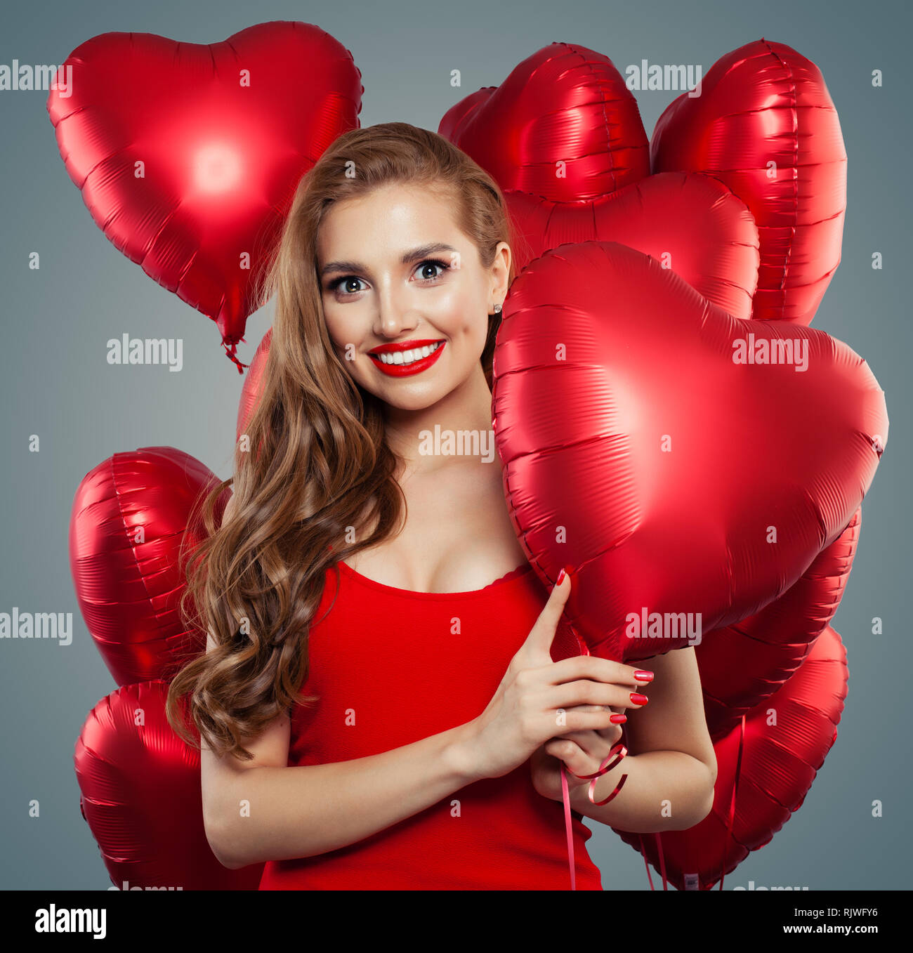 Hübsche junge Frau hält Luftballons. Glückliches Mädchen mit roten Lippen Make-up , Langes lockiges Haar. Valentinstag, Verkauf und Urlaub Party Feier Konzept Stockfoto