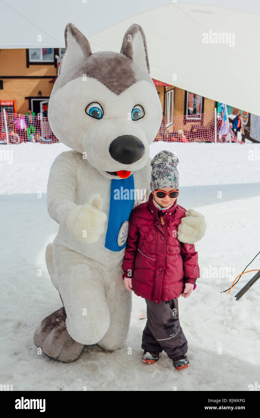 Sheregesh, Kemerovo Region - April 6, 2018. U-Laika Symbol der Universiade 2019 umarmen ein kleines Mädchen. Promo Zone der Universiade Stockfoto