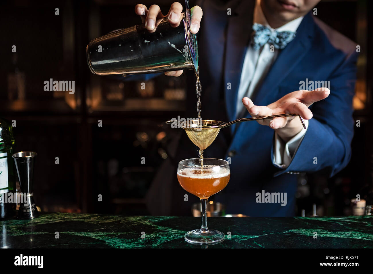 Der Barkeeper streckte den Cocktail doppelt in ein Coupé-Glas Stockfoto