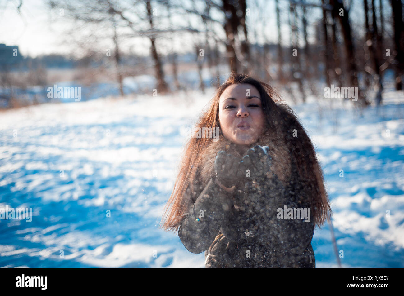 Hübsches Mädchen wirft Schnee im Wald Stockfoto