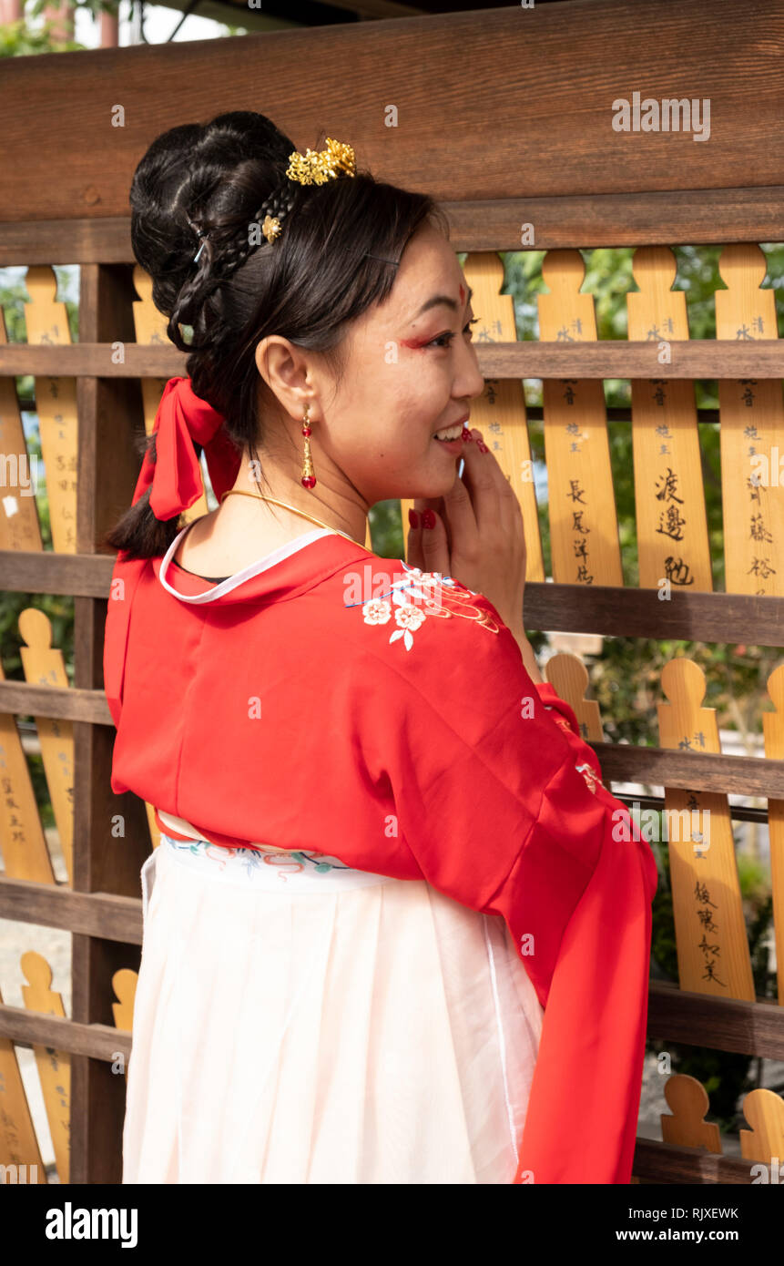 Eine japanische Frau das Tragen eines Kimonos und für ein Foto neben Gebet Bretter am Fushimi Inari Schrein, Kyoto, Japan posing Stockfoto