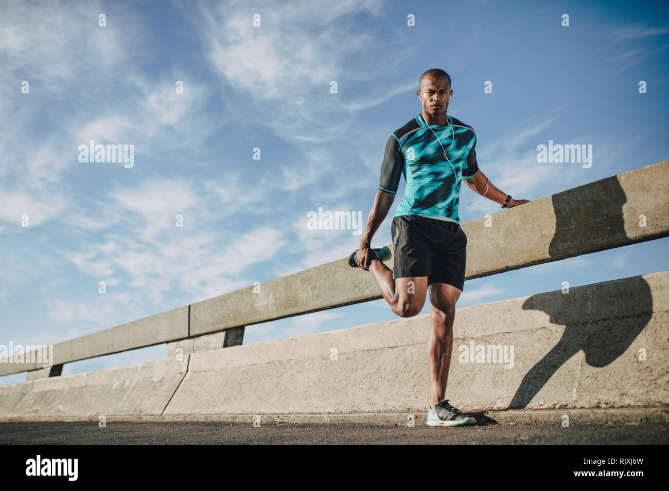 Afrikanische amerikanische Mann in Sportswear stehen an der Straße und Strecken die Beine. Sportsman Aufwärmen vor einem Lauf am Morgen in der Stadt. Stockfoto