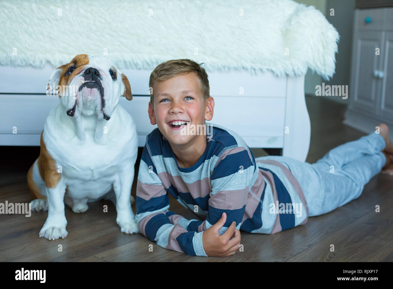 Hübscher junger Junge tragen gemütlichen Schlafanzug spielen mit seinem  Englisch lustig Stier Hund auf dem Boden und genießen das Leben Wochenende  Zeit hängen gegenseitig mit l Stockfotografie - Alamy