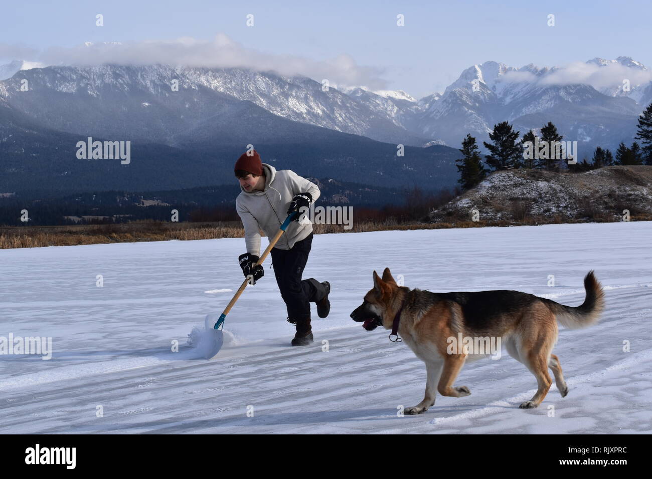 Ein Mann löscht Schnee von einem Outdoor Eislaufbahn auf einem Teich in der Nähe von Invermere, BC, in den kanadischen Rockies Stockfoto