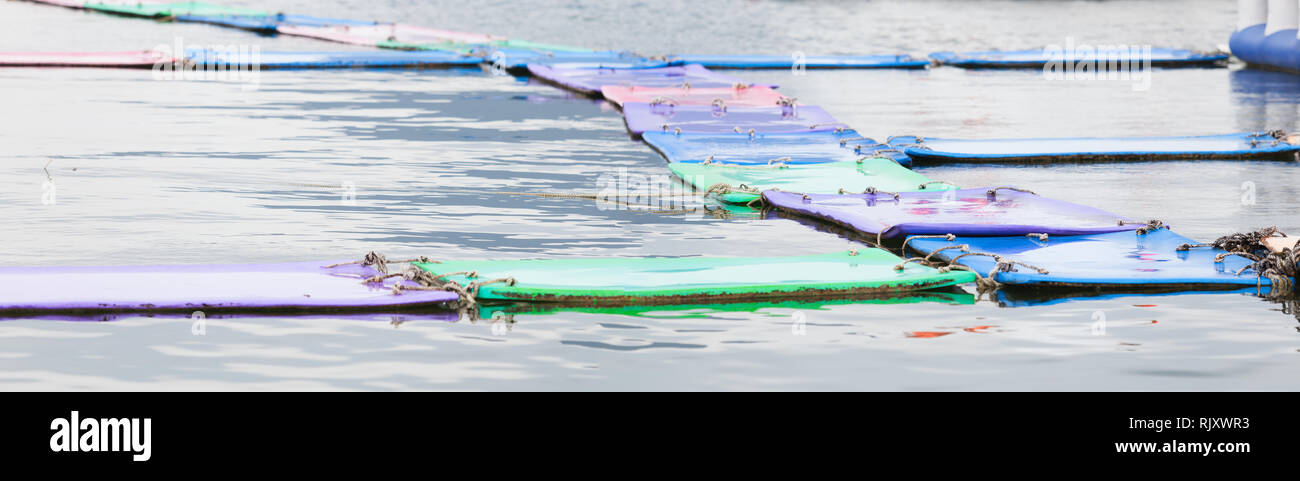 Farbenprächigen schwimmenden Wasser Matten oder Pads auf dem Wasser Hintergrund. Wassersport, Aufblasbare Werkzeug, Erholung, Urlaub, Urlaub, Spaß am Strand, Familie Acti Stockfoto
