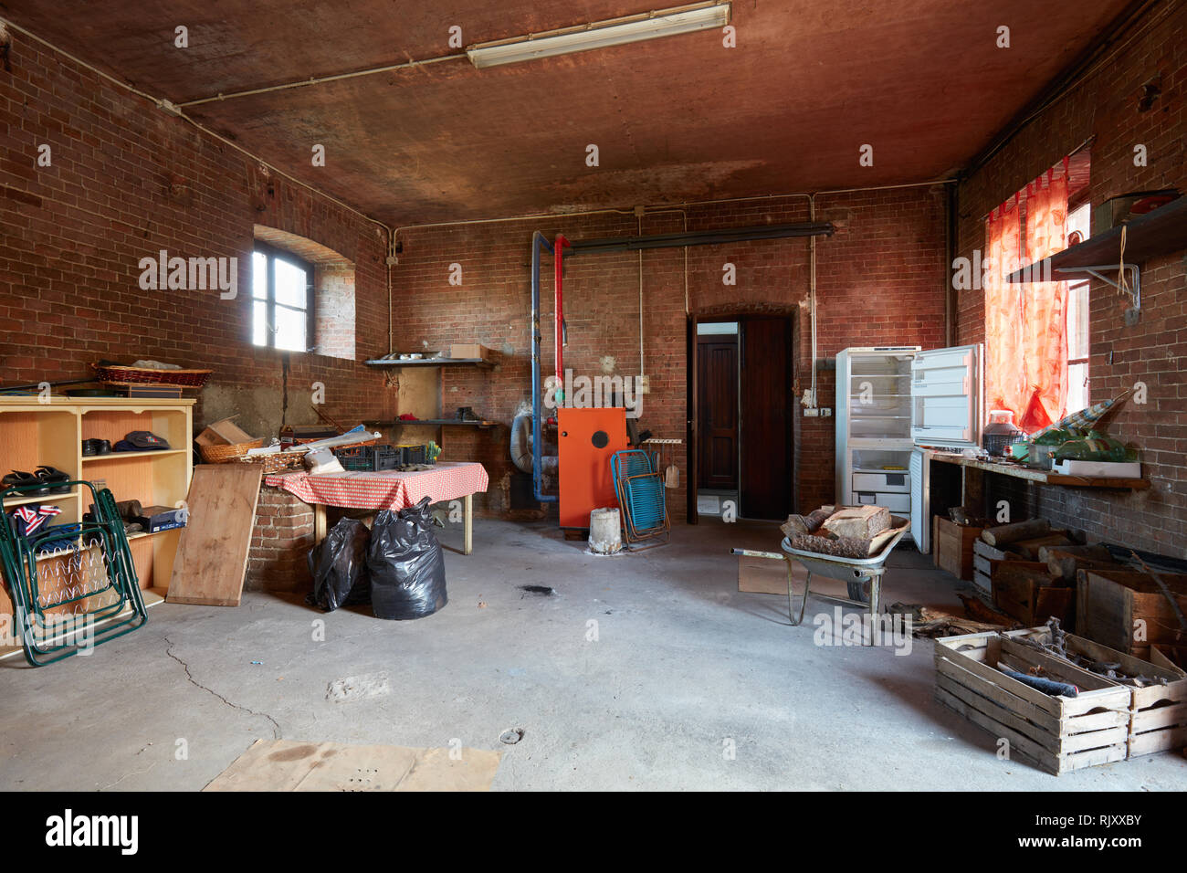 Unordentlicher Keller mit roten Ziegelsteinen Mauern im alten Landhaus Stockfoto