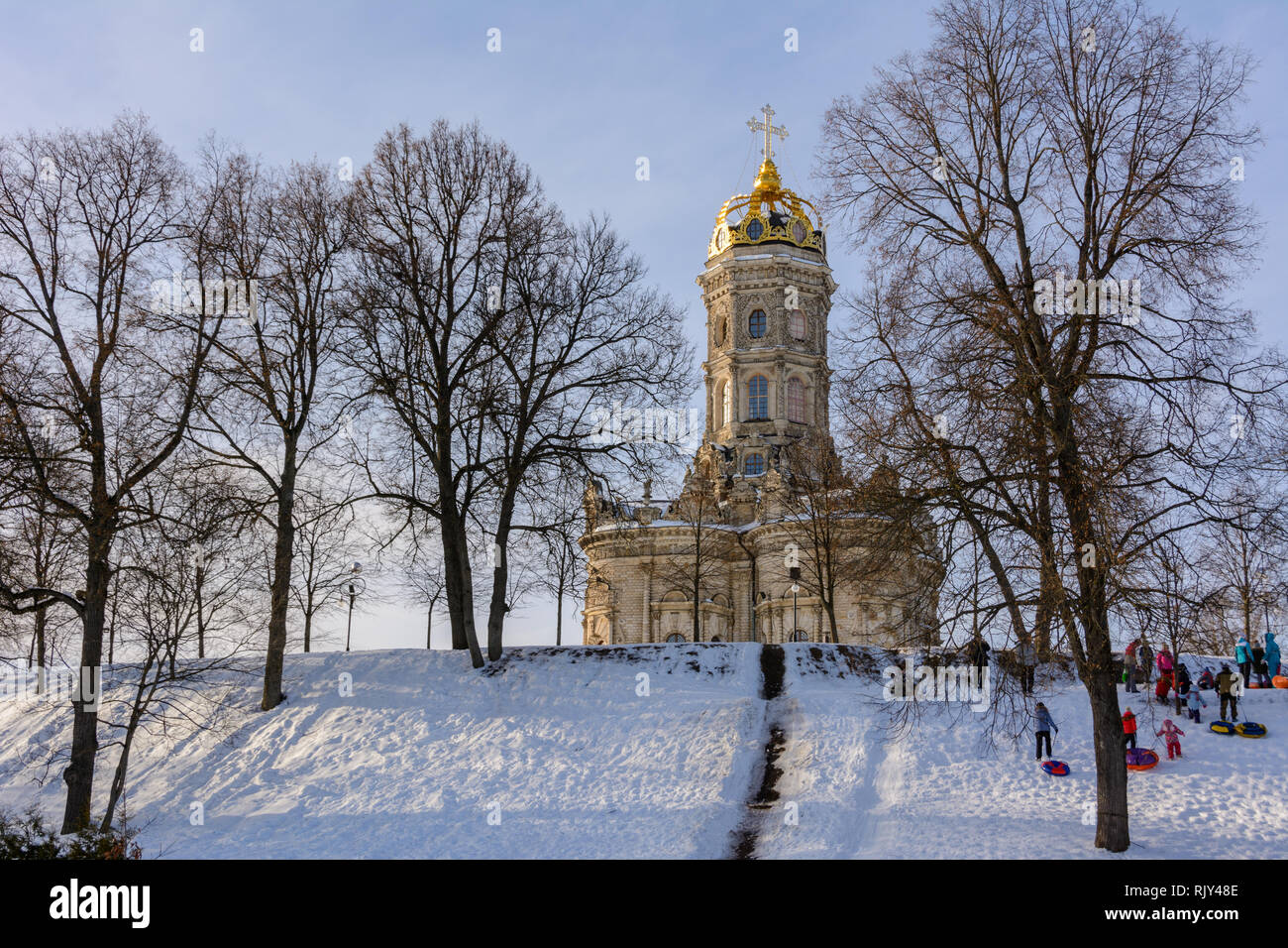 Kinder Fahrt vom Eis Folie an einem sonnigen Wintertag. Winterlandschaft. Tempel der Heiligen Jungfrau in Dubrovitsy in der Region Moskau, Podolsk Russland Stockfoto