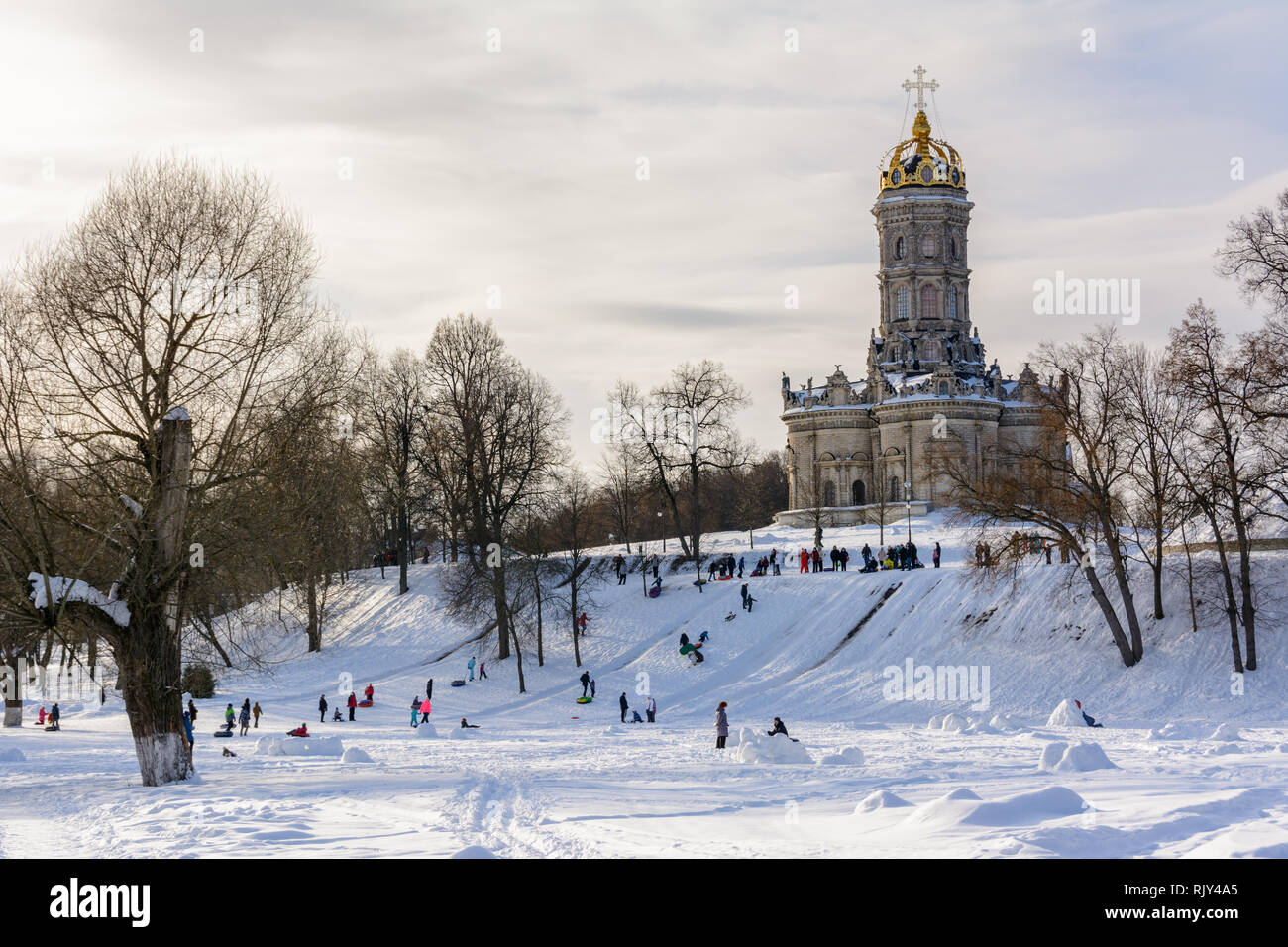 Kinder Fahrt vom Eis Folie an einem sonnigen Wintertag. Winterlandschaft. Tempel der Heiligen Jungfrau in Dubrovitsy in der Region Moskau, Podolsk Russland Stockfoto