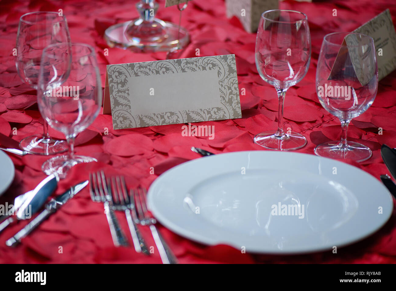 Fine Dining table Ambiente mit weißen China und Wein und Wasser Kristall  Gläser, mit Besteck in der Reihenfolge der Verwendung, und romantisch rot  Tischdecke Stockfotografie - Alamy