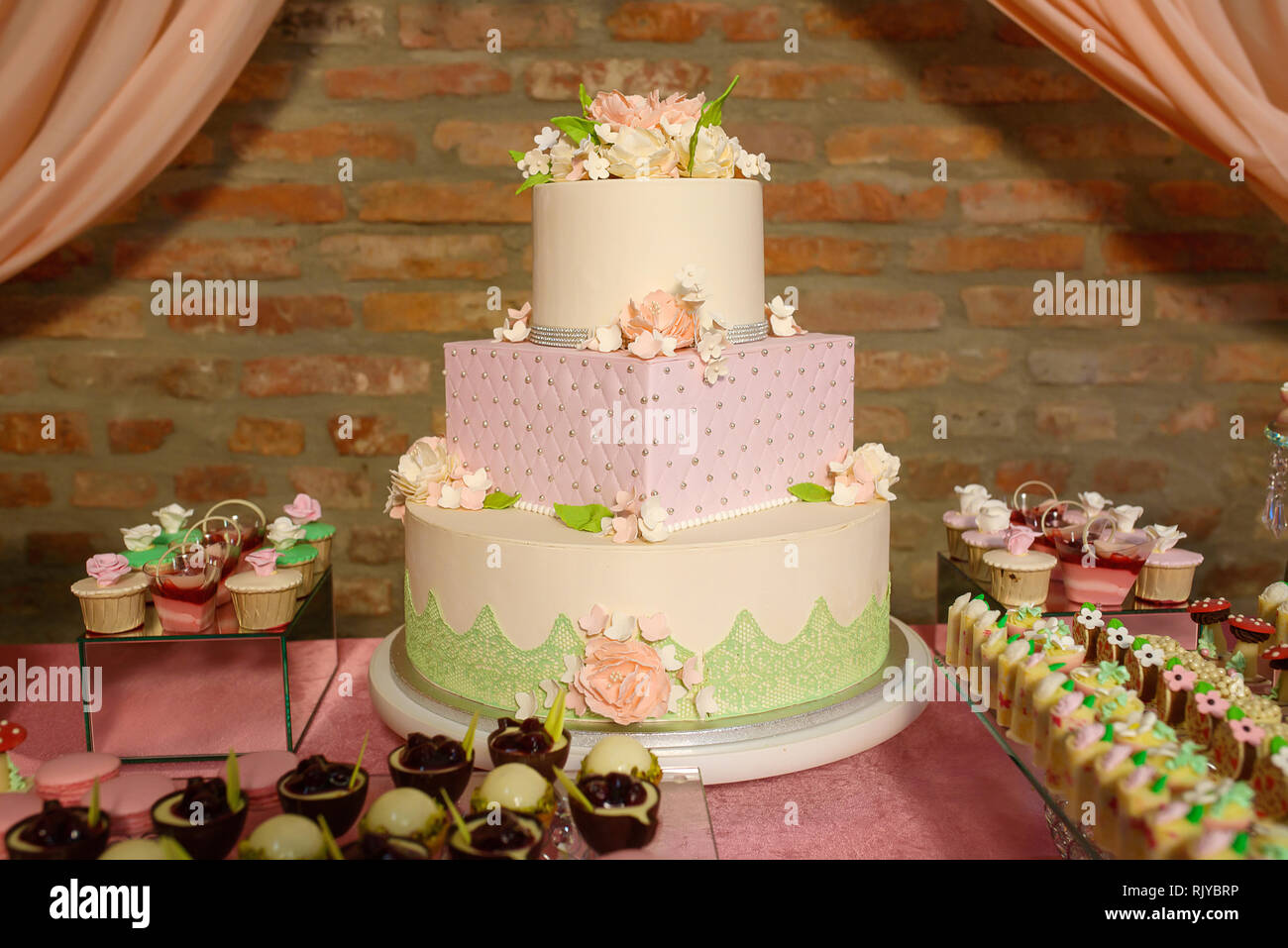 Andere Form drei tiered Kuchen für formelle Veranstaltungen, Hochzeiten oder Geburtstagsfeiern, mit samt Vereisung und Zucker Blumen und essbaren Schmuck verziert Stockfoto