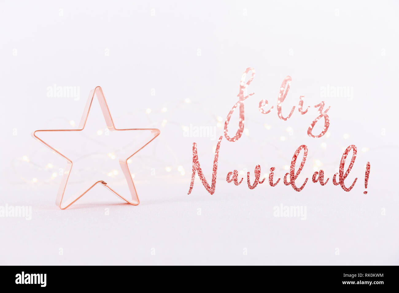 Star Kupfer Cookie Cutter auf weißem Hintergrund mit Bokeh glitzernde Lichter. Urlaub Weihnachten Karte Hintergrund. Horizontale. Urlaub Wortlaut in spanischer Sprache Stockfoto