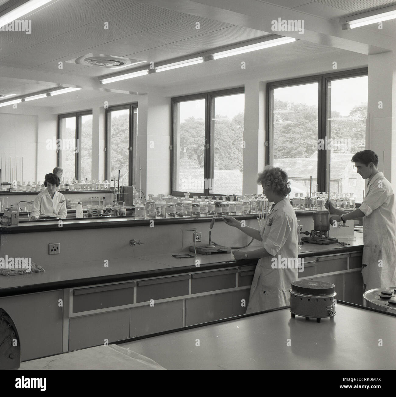 1960 s, junger Erwachsener wissenschaftliche Techniker in Weiß - Mäntel in einem hellen, modernen Labor. Diese Arbeitnehmer sind das Rückgrat der wissenschaftliche Forschung und Untersuchung als ihren Job entials sammeln, vorbereiten und testen Proben. Stockfoto