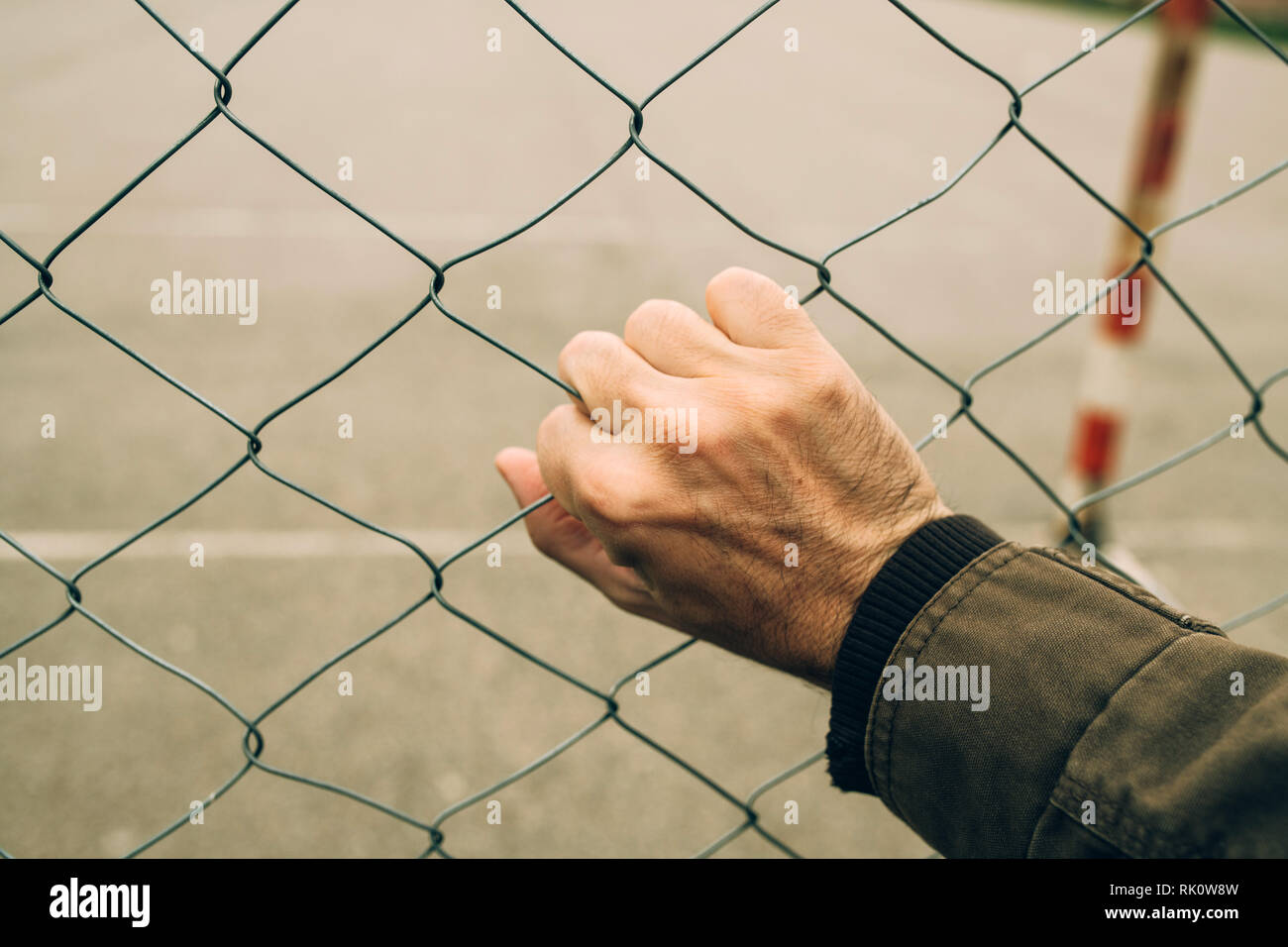 Männliche hand auf chainlink Fence, illegale Einwanderung Konzept Stockfoto