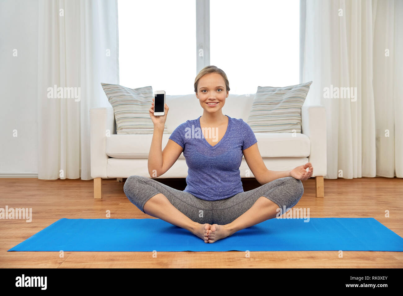 Frau mit Smartphone Yoga zu Hause Stockfoto
