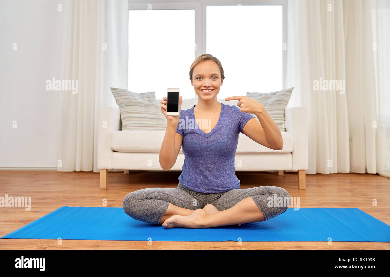 Frau mit Smartphone Yoga zu Hause Stockfoto