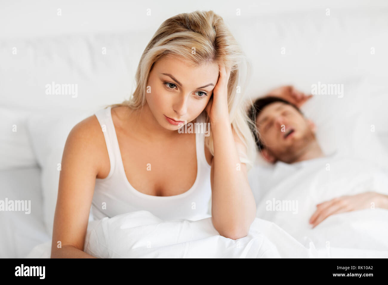 Unglückliche Frau im Bett mit Schnarchen schlafenden Mann Stockfoto