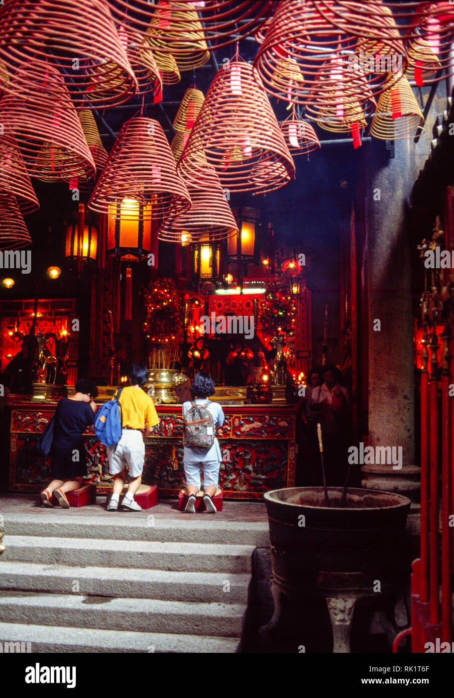 Hong Kong, China; Spulen von Räuchern über eine Familie von Gläubigen in der Man Mo Tempel. Stockfoto