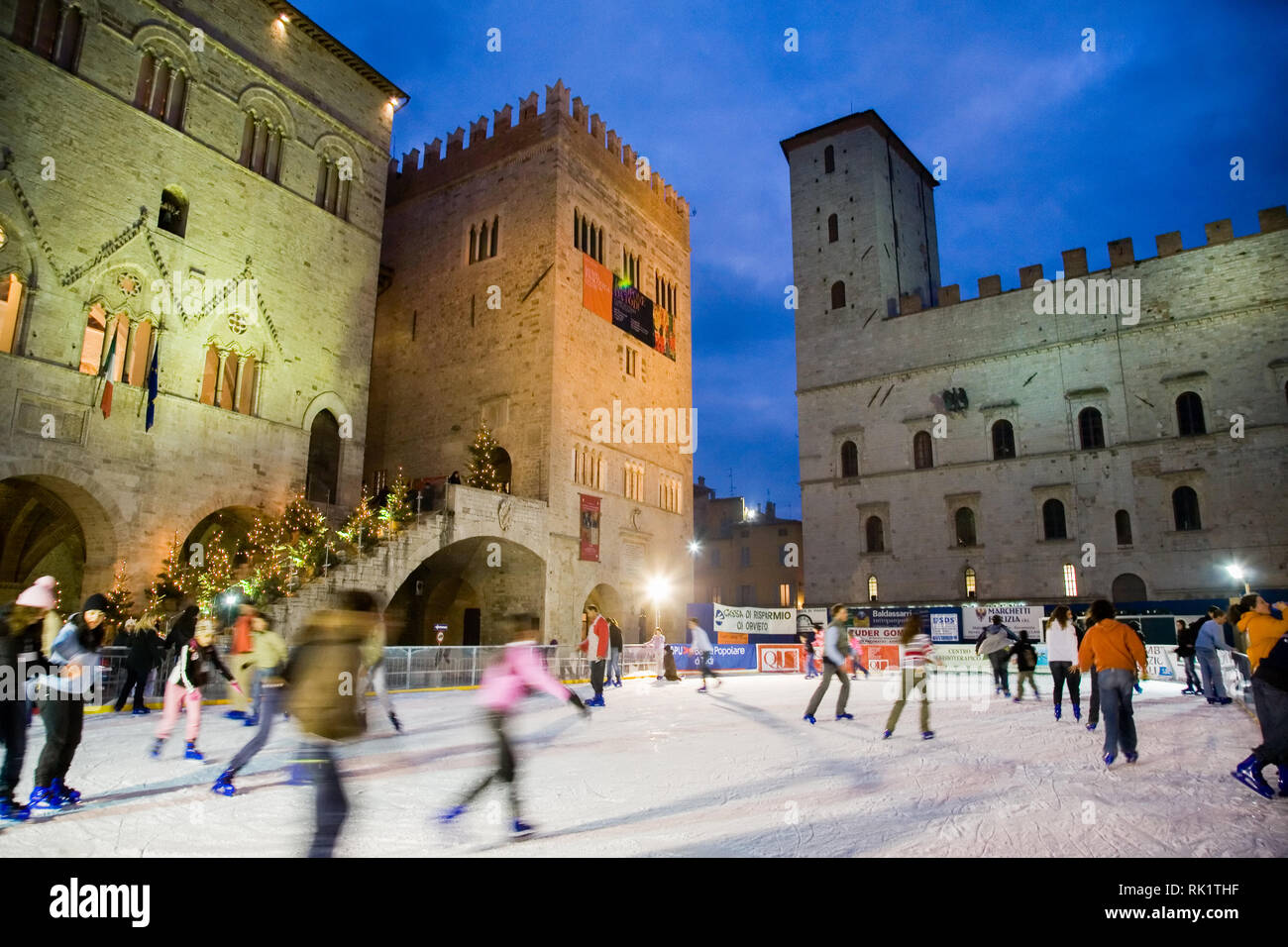 Todi, Italien; Eislaufen in der Dämmerung auf der Piazza del Popolo, von mittelalterlichen Palästen umgeben. Stockfoto