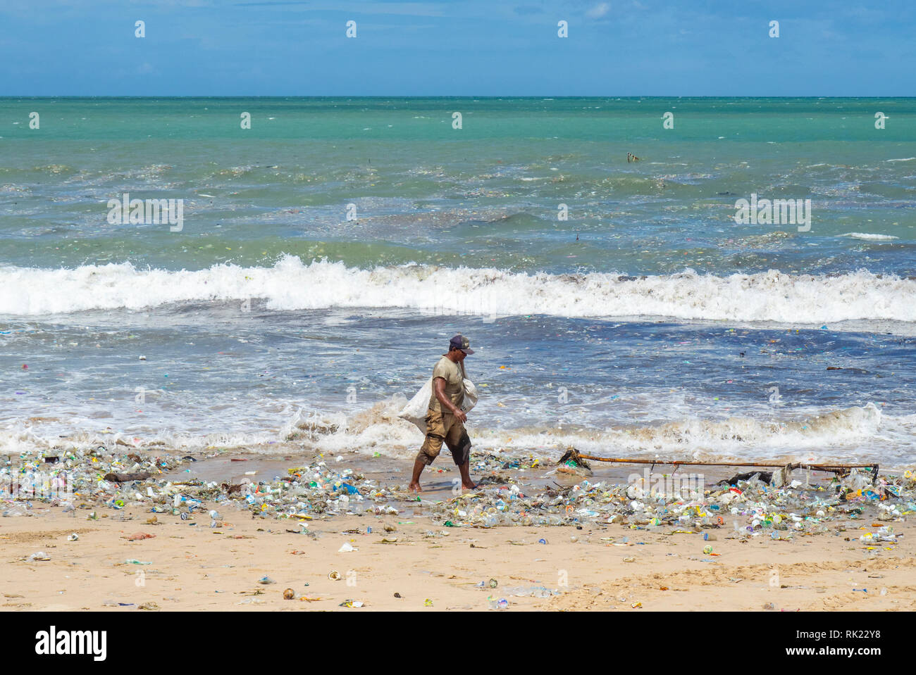 Umweltverschmutzung, einsame Mann herauf Kunststoff Flaschen, Becher, Strohhalme und sonstigem Abfall bis auf den Strand gespült an der Jimbaran Bay, Bali Indonesien.. Stockfoto