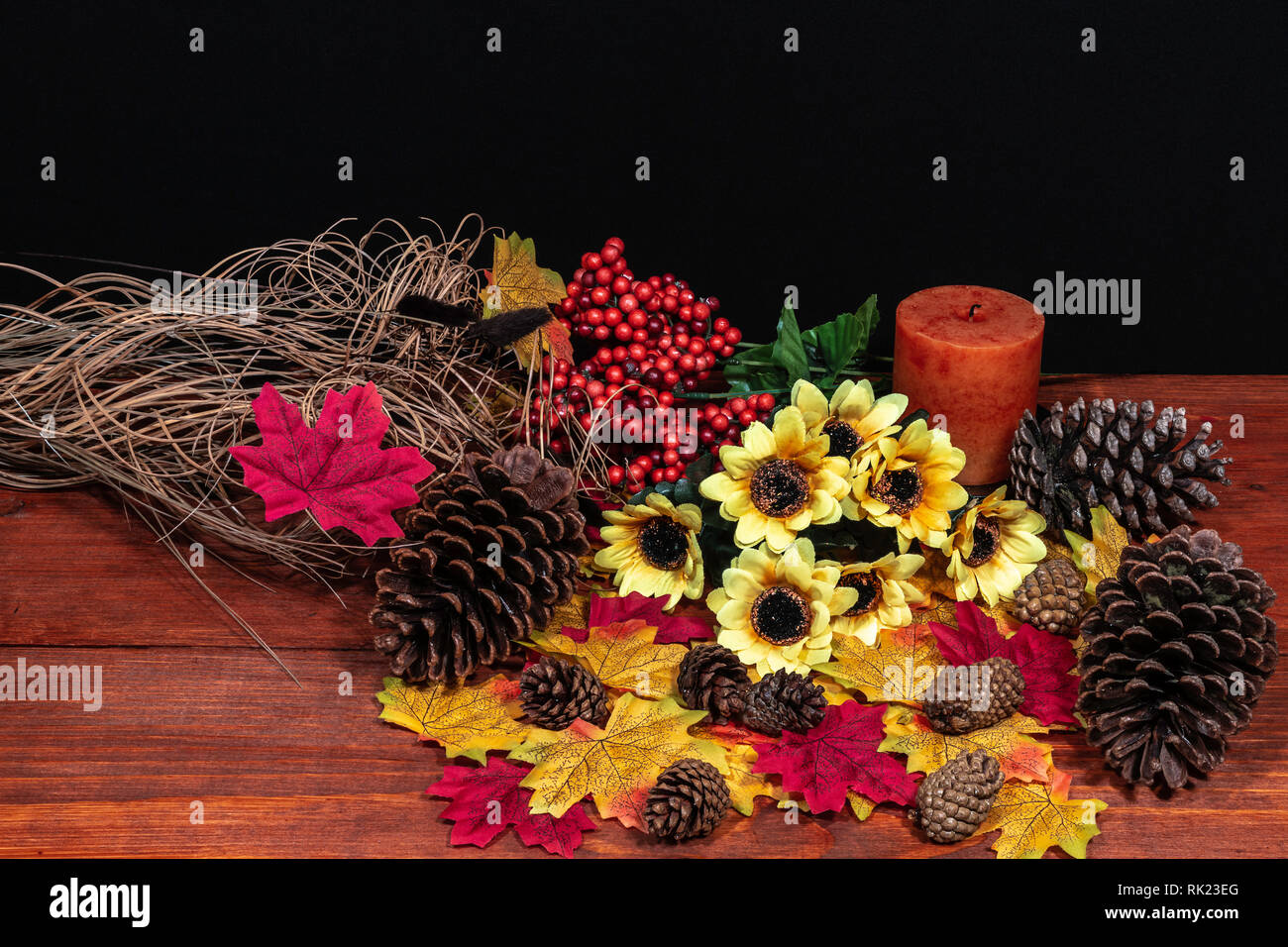 Seide Ahornblätter, schönen Blumenstrauß aus Sonnenblumen, mattierte Kiefernzapfen und orange Kerze auf der Tischplatte mit dunklem Hintergrund. Stockfoto