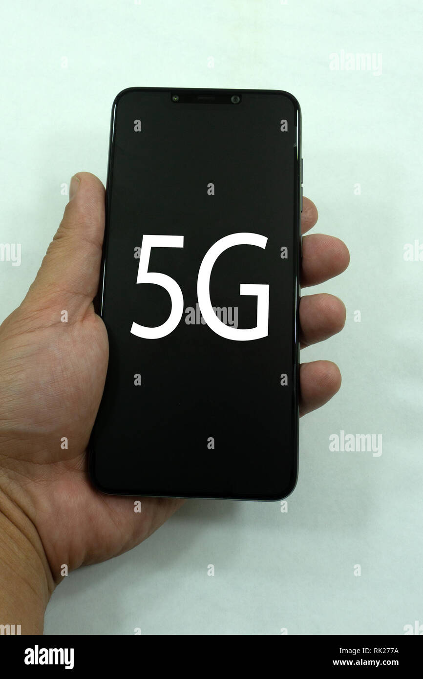 Geschäftsmann sein Telefon mit 5 g über grauer Hintergrund isoliert. Stockfoto