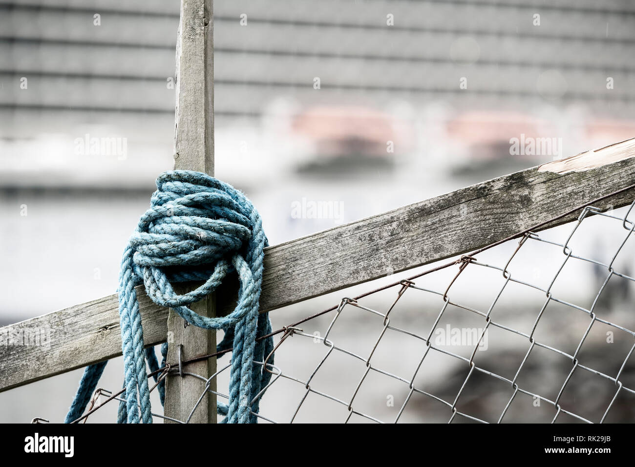 Blau Seil um Holz und Maschendrahtzaun gewickelt, Kreuzfahrt Schiff im Hintergrund Stockfoto