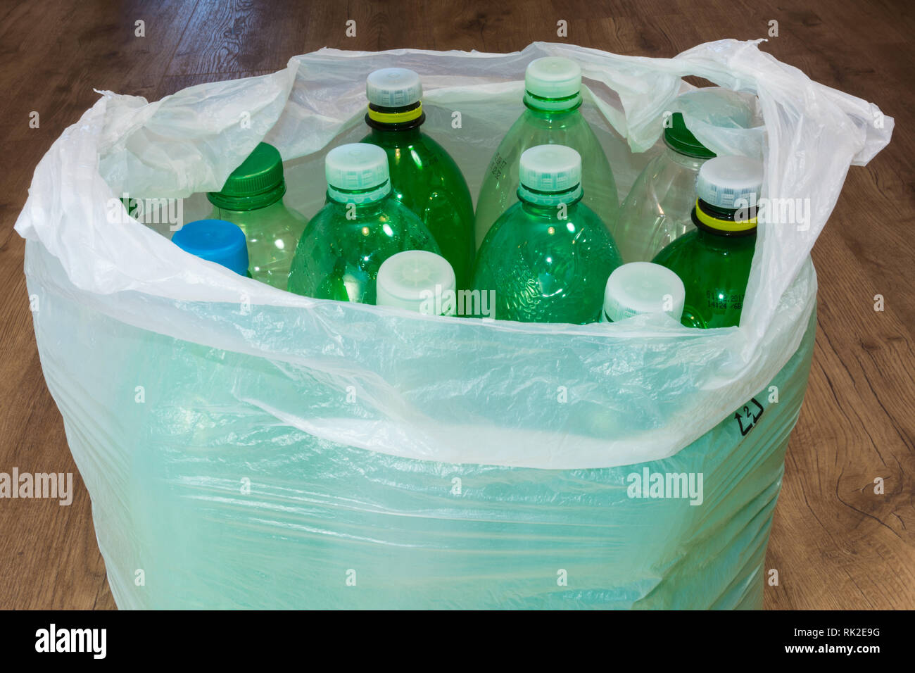 Detail von leeren Plastikflaschen in einer Tragetasche auf Holzboden. Ökologische Sortierung und Entsorgung von Hausmüll. Kontamination von e-Umgebung. Stockfoto