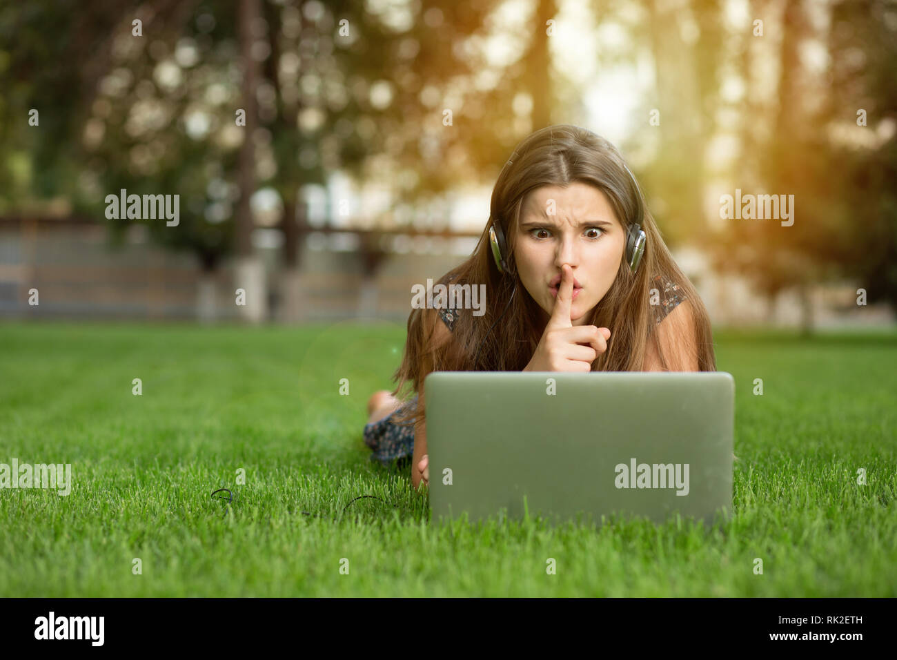 Jugendlicher Schüler Frau, die an einem Notebook arbeitet, hush Schild draußen liegen auf grünen Rasen Kopfhörer auf den Kopf. Multikulturelle Modell gemischten Rennen asiatische Stockfoto