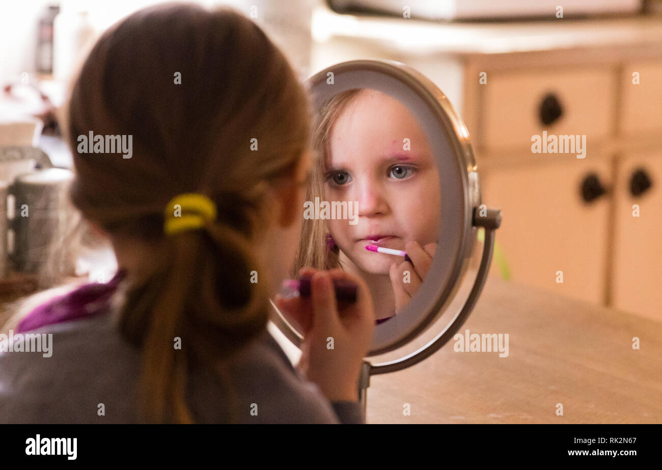 Ein 3 Jahre alter schaut in den Spiegel und Anwendung bilden. Stockfoto