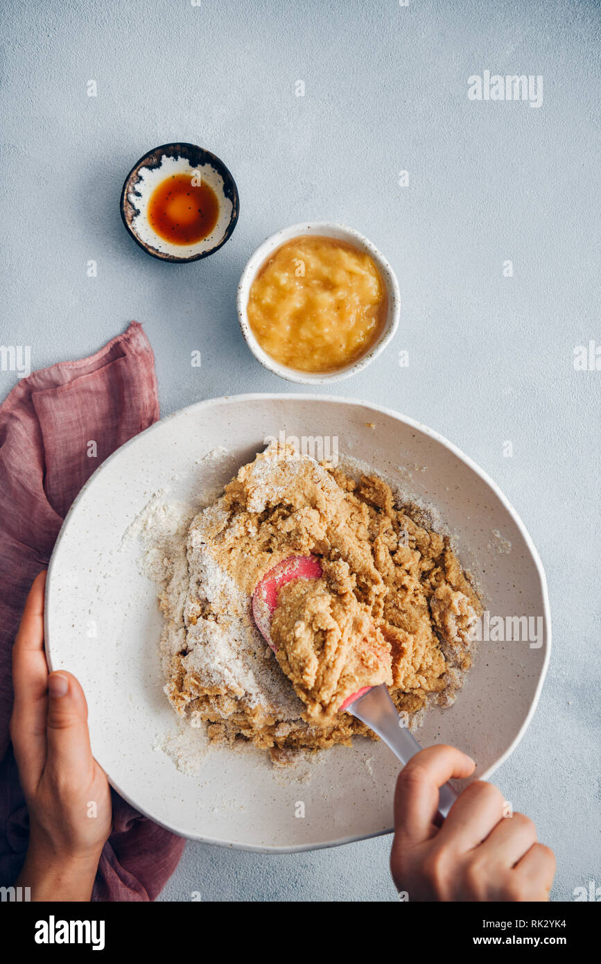 Frau die Kombination der Zutaten für vegane Peanut butter Cookie Dough mit einem Teigschaber in einem handgefertigte Keramik Schüssel. Stockfoto