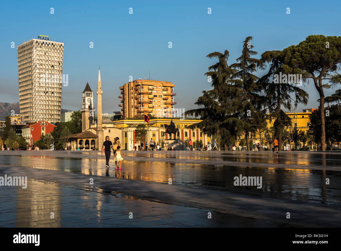 Junge Familie und andere einheimische auf Skanderbeg Platz vor dem Skanderbeg Statue, Et'Hem Bey Moschee und ein Hotel, Tirana, Albanien Stockfoto