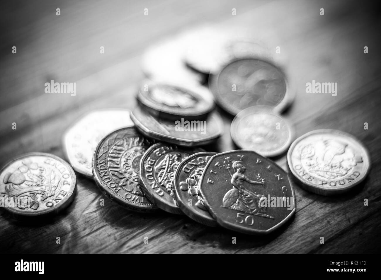 Neues Britisches Pfund GBP Münzen Festlegung beiläufig auf schwarze Brieftasche auf Holz- Oberfläche. Reichtum, Geld, Bargeld, ändern. Stockfoto