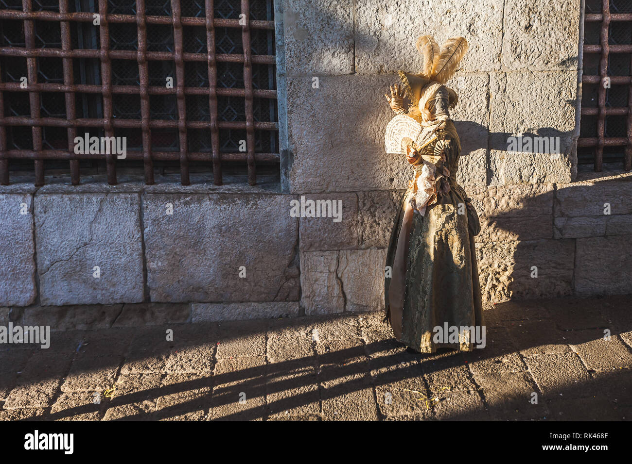 Venedig, Italien - 10 Februar 2018: Karneval Maske in Gold gekleidet, lehnte sich gegen die Gefängnisse Wand Stockfoto