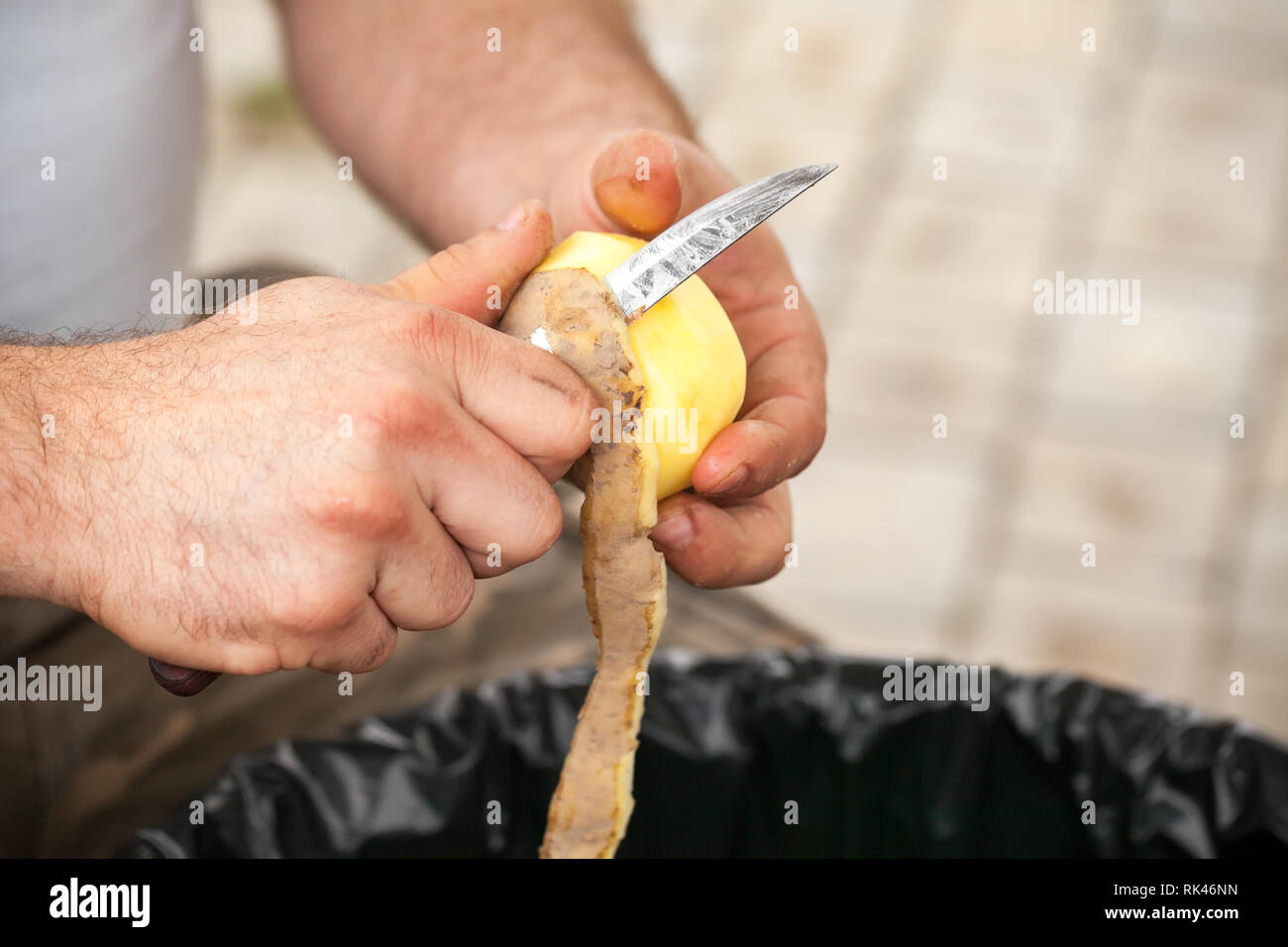 Rohe Kartoffel schälen. Hände von Cook mit Messer, Nahaufnahme mit selektiven Fokus Stockfoto