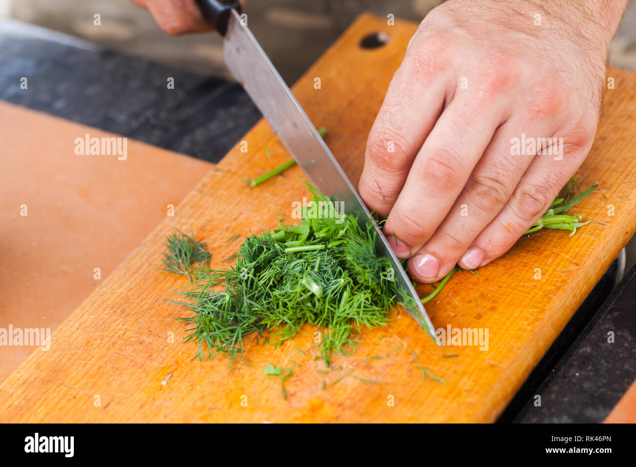 Grünen hacken. Männliche hand mit Messer, Nahaufnahme, selektiver Fokus Stockfoto