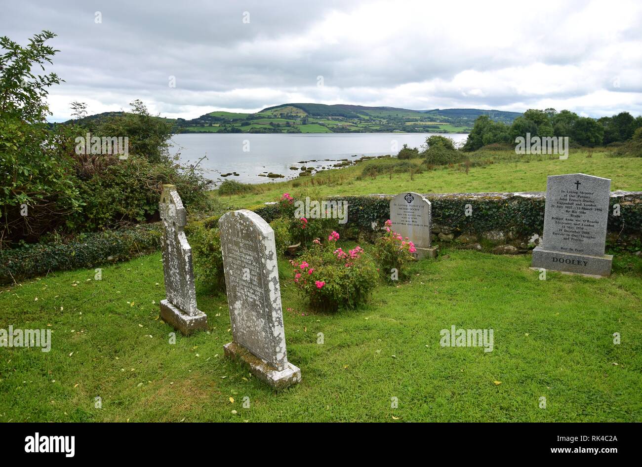 Grabsteine mit Inschriften auf Friedhof auf der heiligen Insel im Lough Derg in Irland, County Clare. In der Rückseite Lough Derg. Stockfoto