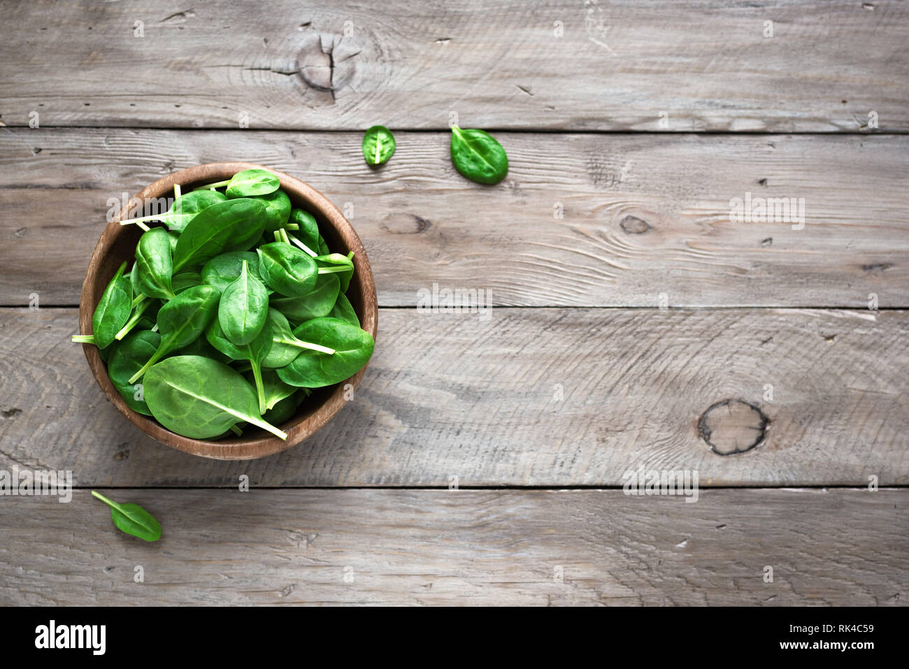Grün baby Spinatblätter in Schüssel auf Holz- Hintergrund, Ansicht von oben, kopieren. Sauber Essen, Detox, Diät Lebensmittel Zutat - grün Bio Spinat. Stockfoto
