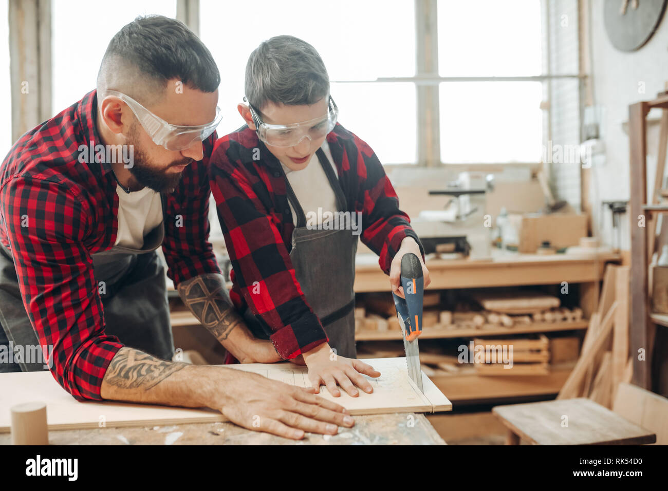 Erfahrene Lehrer der Zimmerhandwerk-fähigkeit macht ein Junge, mit kunst von Holzbearbeitung. Zusammen mit Erwachsenen Handwerk mentor Kind lernt zu Sägen, Bohren, Gr Stockfoto