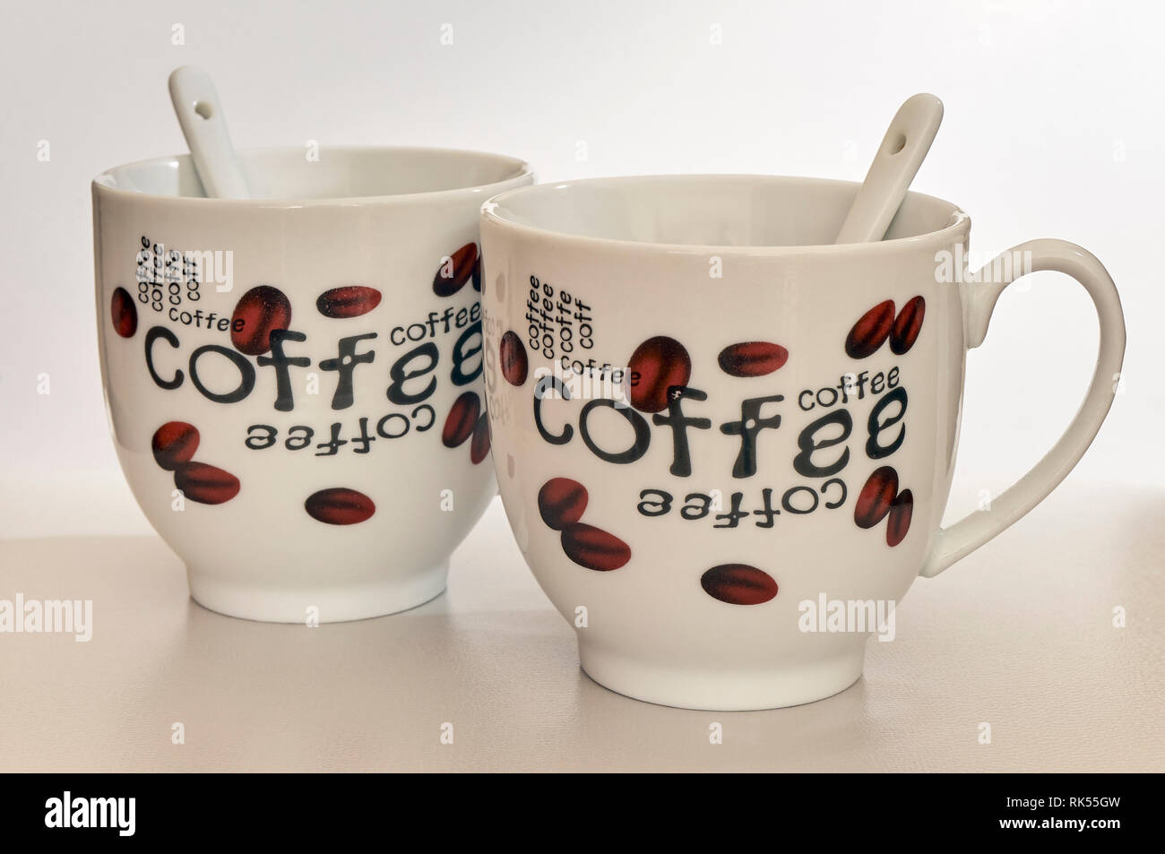 Zwei Tassen Kaffee mit ihren Löffel mit Kaffeebohnen und das Wort Kaffee lackiert Stockfoto