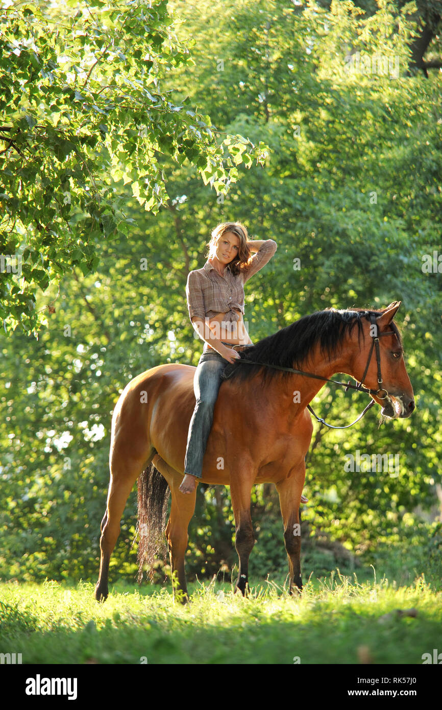 Schöne cowgirl Bareback ihr Pferd im Wald Lichtung bei Sonnenuntergang Stockfoto
