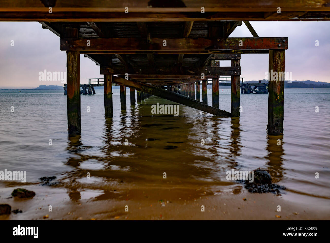 Landschaft Foto unter Lake Drive Pier ab Shoreline unter bewölktem Himmel auf einer inneren Hafen Strand, Poole, Dorset. Stockfoto