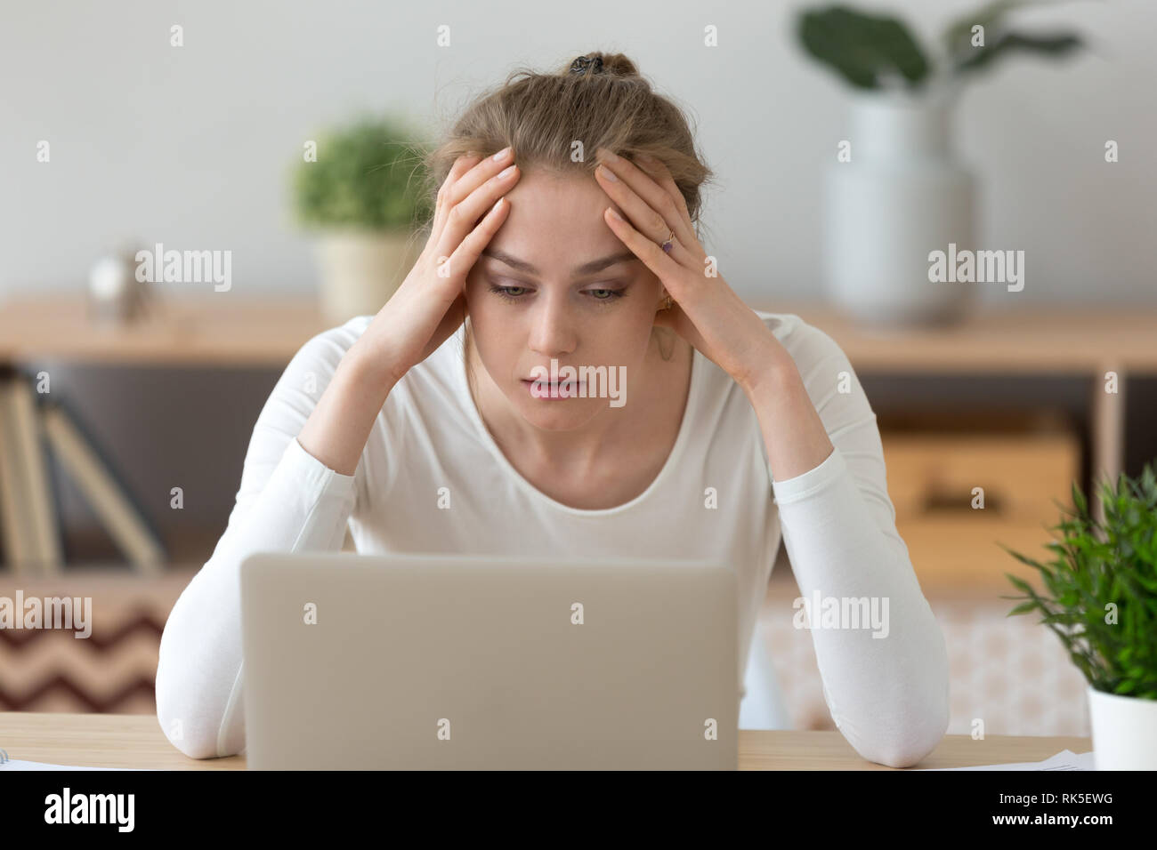 Junge Frau mit Laptop lesen schlechte Internet Nachrichten betonte Stockfoto